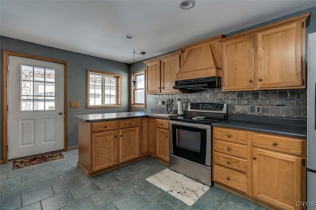 kitchen featuring dark countertops, a peninsula, stainless steel electric range, under cabinet range hood, and pendant lighting