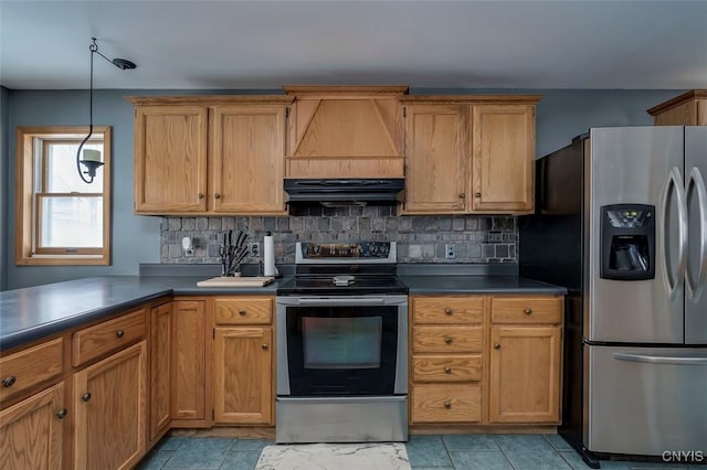 kitchen with under cabinet range hood, hanging light fixtures, appliances with stainless steel finishes, decorative backsplash, and dark countertops