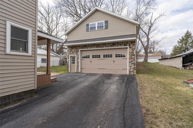 view of front facade featuring a front yard, stone siding, and driveway
