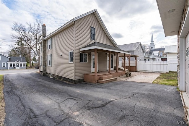 view of front of home with a porch, fence, and a chimney
