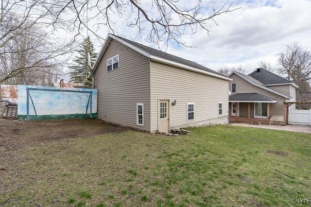 back of house with a yard, fence, and a pool