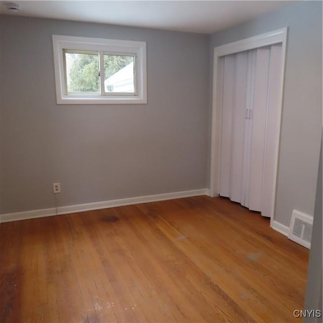 unfurnished bedroom with light wood finished floors, baseboards, visible vents, and a closet