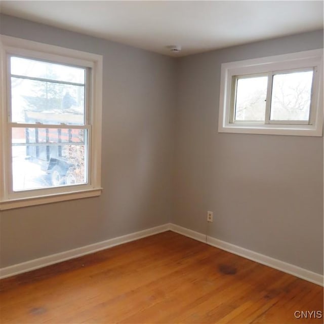 spare room with a healthy amount of sunlight, light wood finished floors, and baseboards