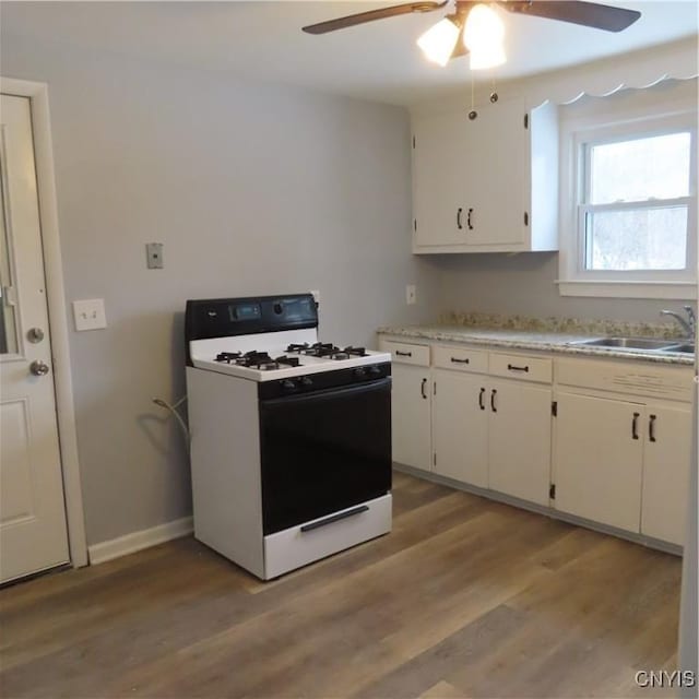 kitchen featuring light countertops, white cabinets, a sink, gas range, and light wood-type flooring