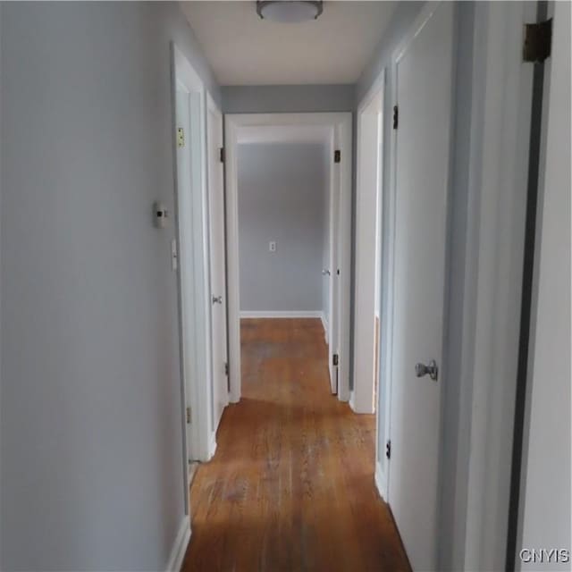 hallway featuring baseboards and wood finished floors