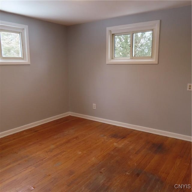 spare room featuring a healthy amount of sunlight, baseboards, and wood finished floors