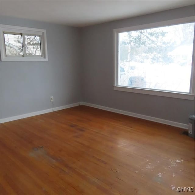 spare room with baseboards and wood finished floors