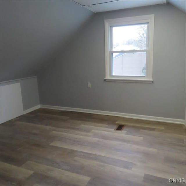 additional living space featuring vaulted ceiling, baseboards, and wood finished floors