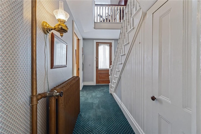 doorway featuring dark carpet, stairway, and baseboards