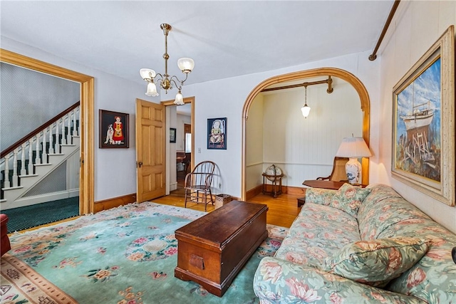 living room with stairs, baseboards, wood finished floors, and a notable chandelier