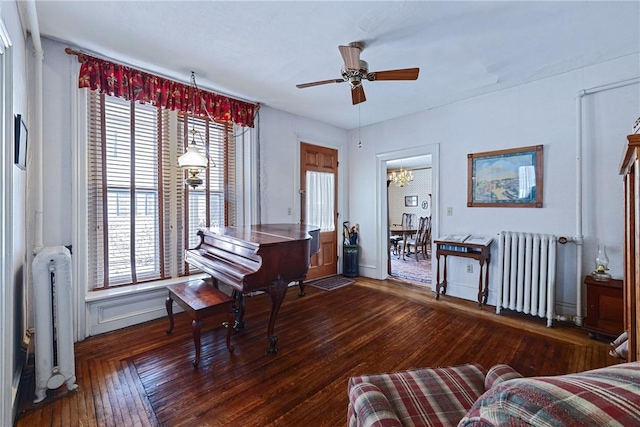 living area featuring dark wood finished floors, a ceiling fan, and radiator