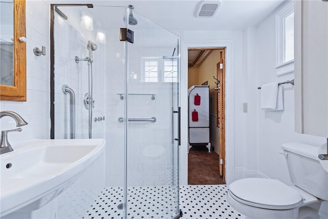 bathroom with visible vents, a sink, a shower stall, and toilet