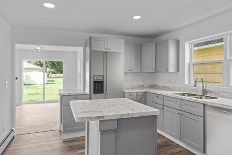 kitchen with a baseboard heating unit, a sink, a kitchen island, and gray cabinetry