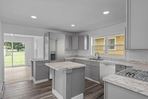 kitchen with dark wood-style floors, a kitchen island, gray cabinets, a sink, and recessed lighting