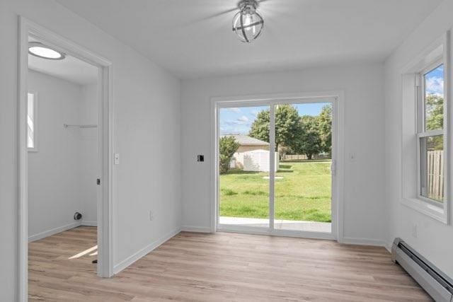 doorway to outside featuring light wood-type flooring, baseboards, and baseboard heating