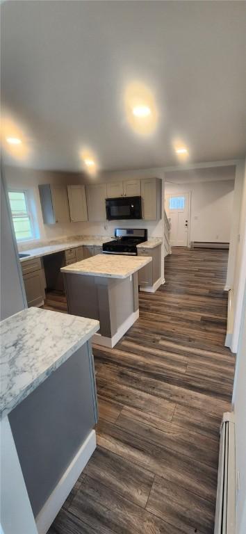 kitchen with electric stove, a center island, black microwave, and a baseboard heating unit