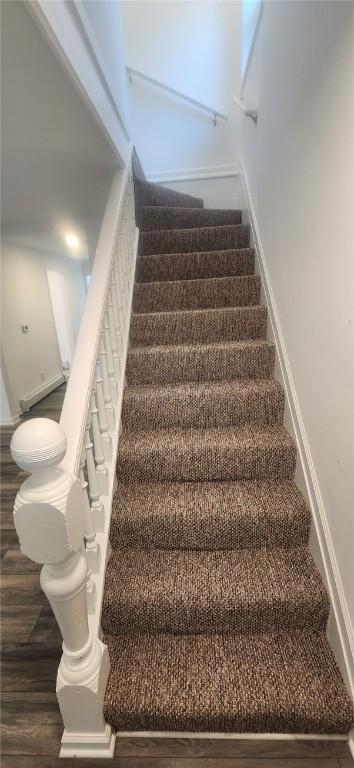 staircase featuring wood finished floors and baseboards