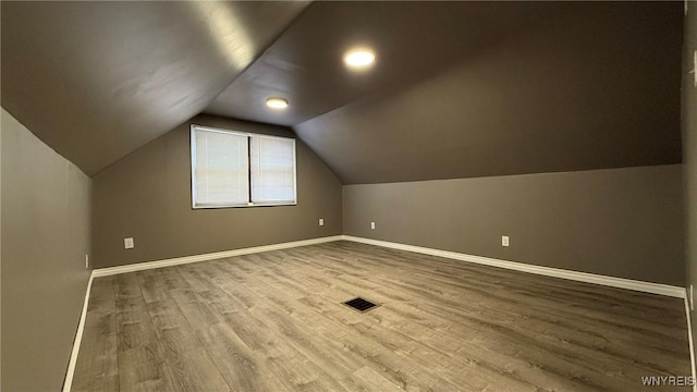 bonus room with vaulted ceiling, wood finished floors, visible vents, and baseboards