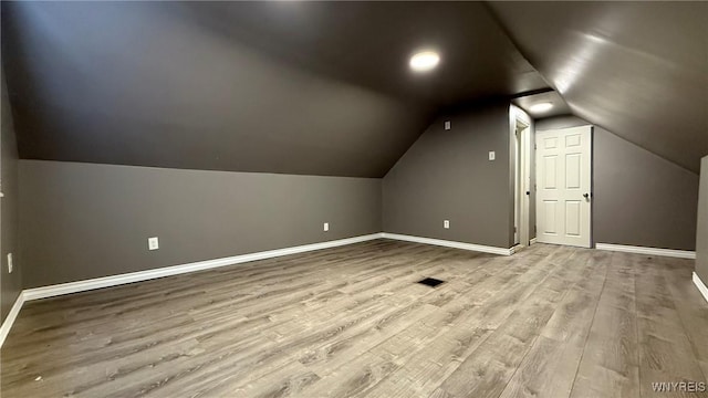 additional living space with lofted ceiling, wood finished floors, and baseboards