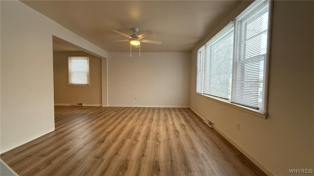 empty room featuring baseboards, light wood-type flooring, visible vents, and a ceiling fan