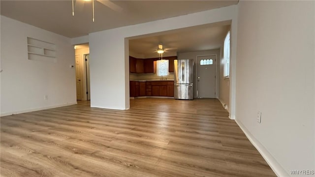 unfurnished living room with baseboards, a ceiling fan, and wood finished floors