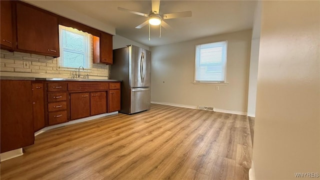 kitchen featuring light wood-type flooring, visible vents, a sink, and freestanding refrigerator