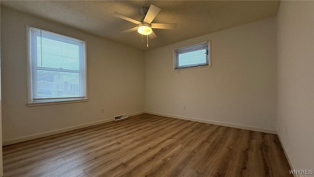 empty room with visible vents, ceiling fan, baseboards, and wood finished floors