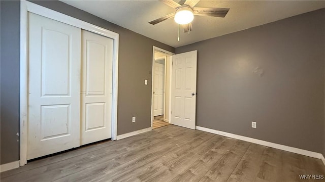 unfurnished bedroom with a closet, ceiling fan, baseboards, and wood finished floors