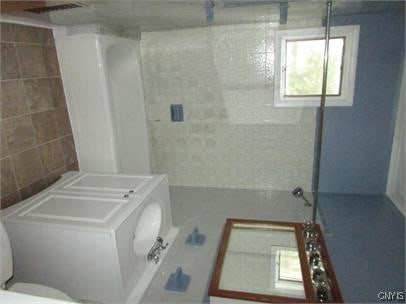 bathroom featuring washer / dryer, toilet, and walk in shower