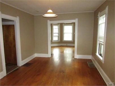 interior space with ornamental molding, dark wood-style flooring, visible vents, and baseboards