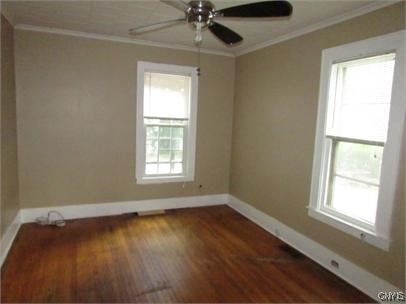 unfurnished room featuring ornamental molding, a healthy amount of sunlight, and baseboards