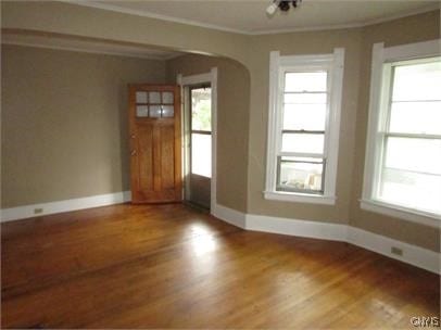 interior space featuring a healthy amount of sunlight, arched walkways, and ornamental molding