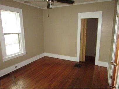 unfurnished room featuring a ceiling fan, baseboards, ornamental molding, and dark wood-style flooring