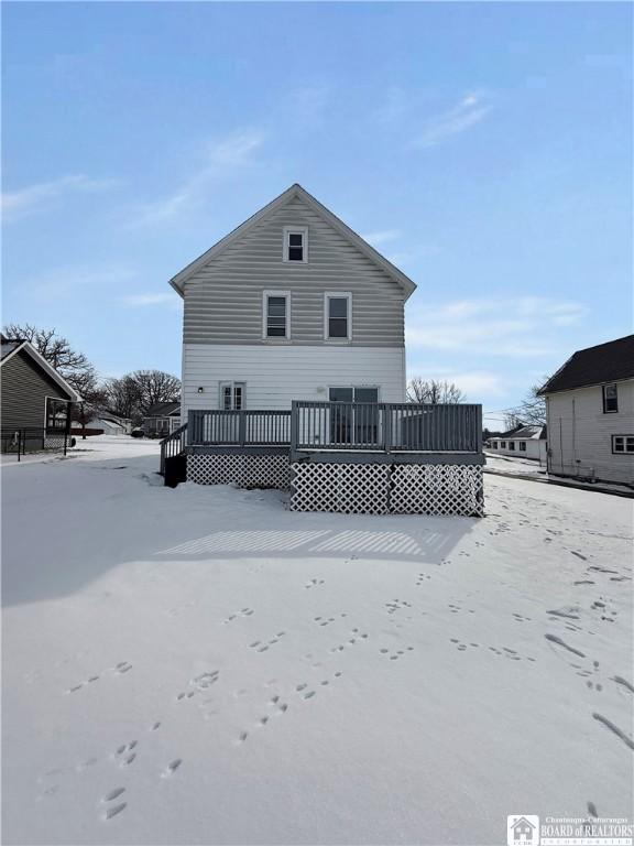 snow covered rear of property with a wooden deck