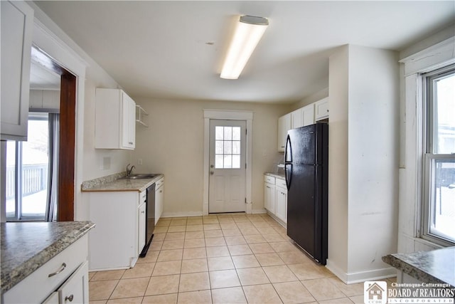 kitchen featuring a wealth of natural light, freestanding refrigerator, stainless steel dishwasher, white cabinetry, and a sink