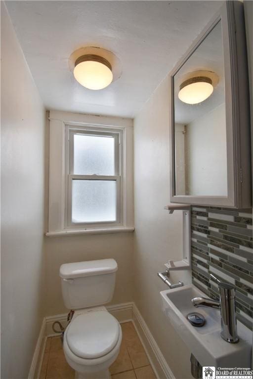 bathroom with baseboards, backsplash, toilet, and tile patterned floors