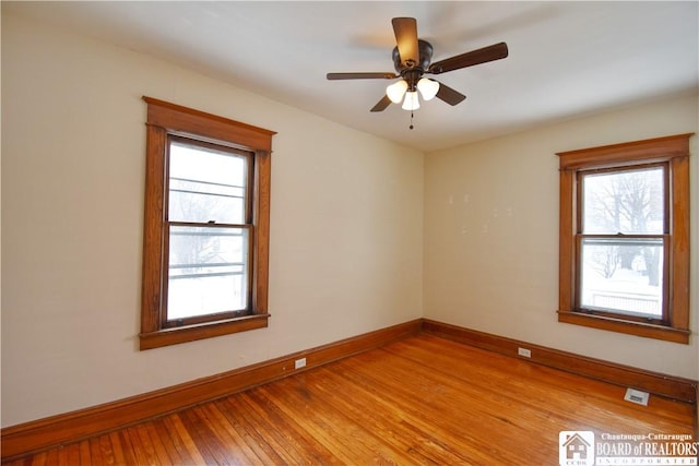 spare room with light wood-style floors, ceiling fan, and baseboards