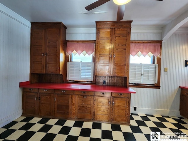 kitchen with a ceiling fan, light floors, baseboards, arched walkways, and dark countertops