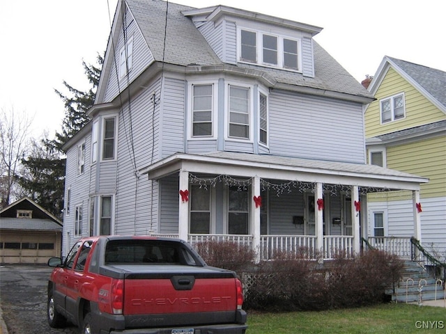 view of front of home featuring a garage, a shingled roof, a porch, and an outdoor structure