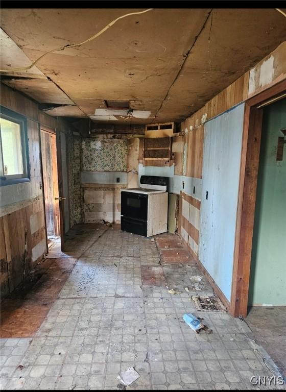 kitchen with electric stove, wooden walls, and light floors