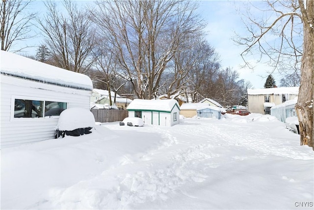 yard layered in snow with an outdoor structure and fence