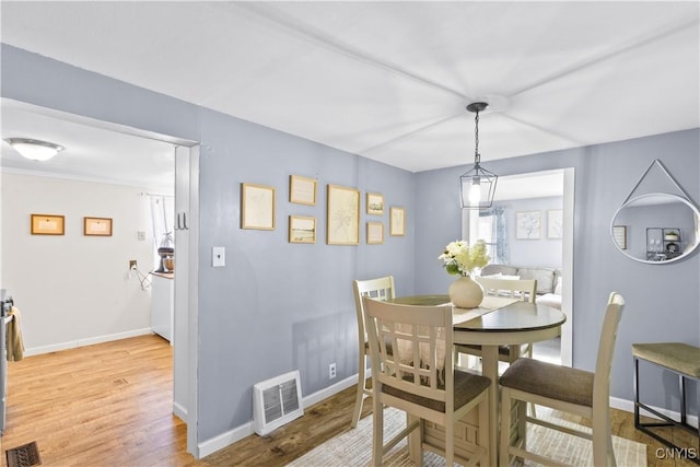 dining room featuring wood finished floors, visible vents, and baseboards