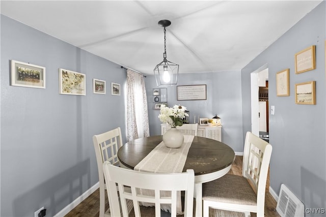 dining room with dark wood finished floors, visible vents, and baseboards