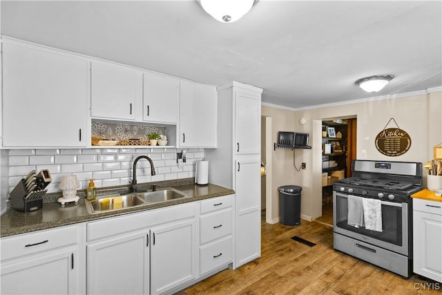 kitchen featuring stainless steel gas range oven, white cabinets, light wood-type flooring, open shelves, and a sink