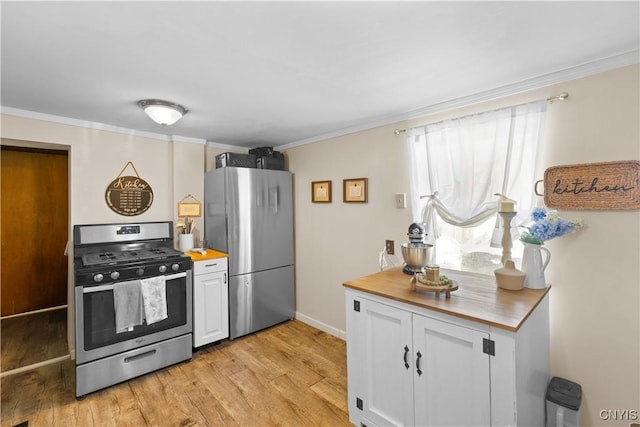 kitchen with stainless steel appliances, white cabinetry, ornamental molding, and light wood finished floors