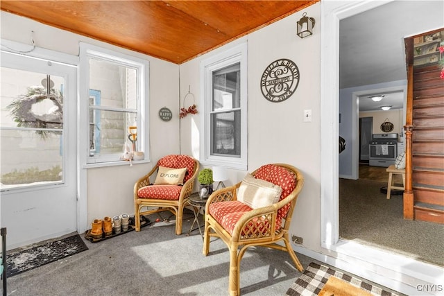 sitting room with carpet floors, wooden ceiling, and stairway