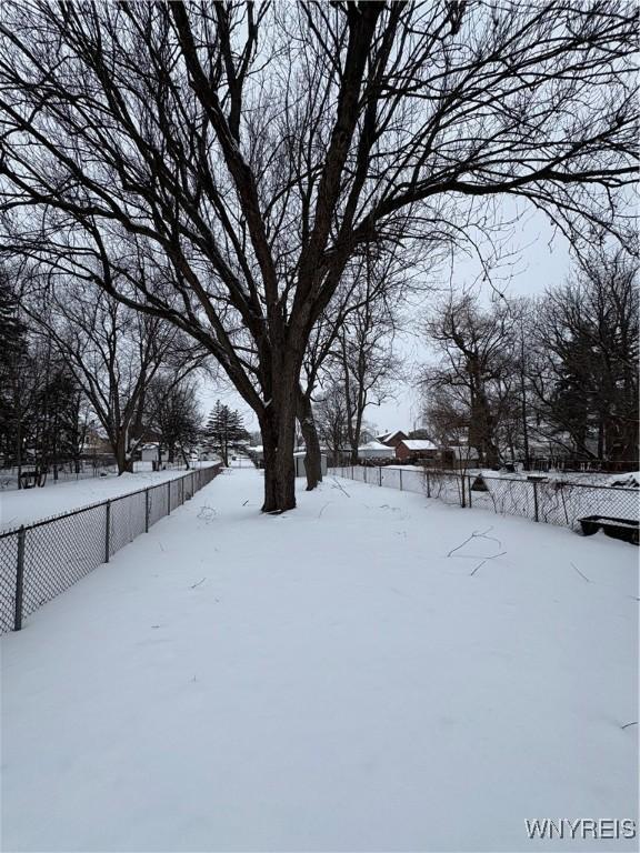 yard layered in snow featuring fence