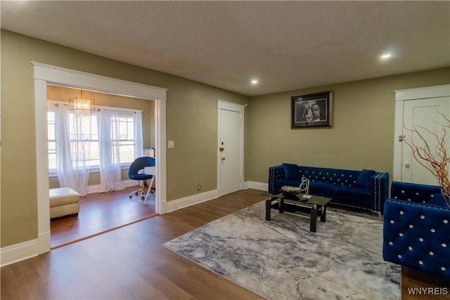 living area featuring a textured ceiling, baseboards, wood finished floors, and recessed lighting