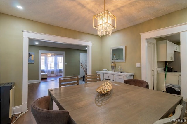 dining space featuring recessed lighting, dark wood-style flooring, a notable chandelier, and baseboards