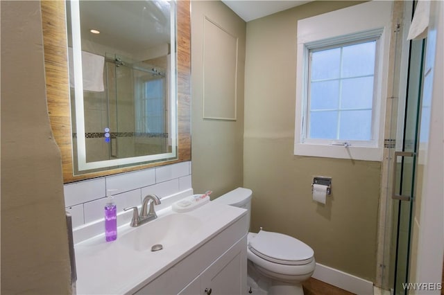 bathroom with tasteful backsplash, toilet, a shower stall, vanity, and baseboards